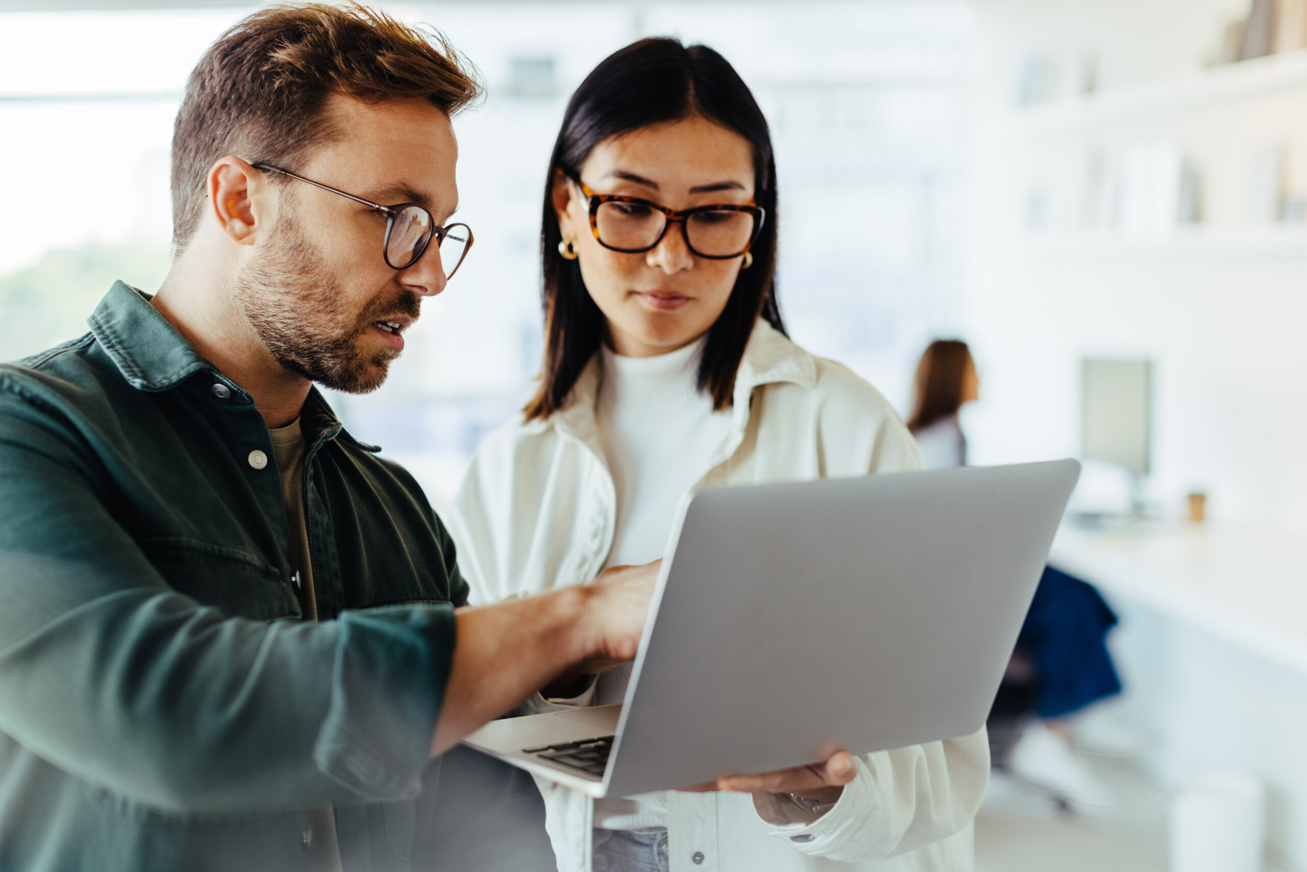 Man and woman standing in an office and using a laptop together